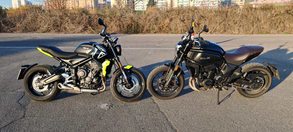 Dos motocicletas modernas estacionadas en un camino, una de color negro con detalles amarillos y otra negra con un asiento marrón.